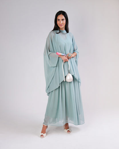 Model wearing the sage Élan dress, showing its layered silhouette in motion.