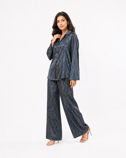 Studio view of the Sahara Bloom turquoise silk two-piece set with a relaxed shirt and matching geometric-print trousers.