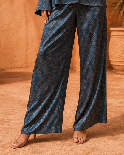 Close-up of Sahara Bloom wide-leg silk trousers showing the deep turquoise and bronze geometric print.