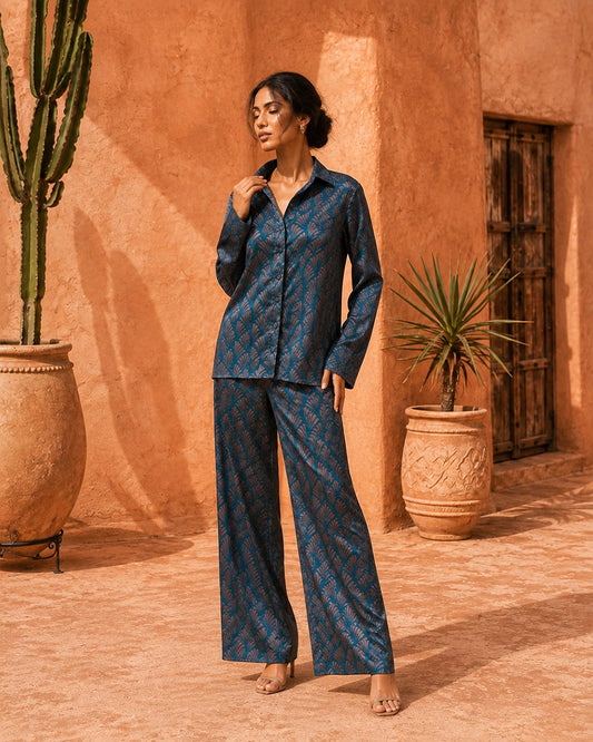 Model wearing the Sahara Bloom turquoise and bronze silk co-ord set with a button-front shirt and wide-leg trousers.