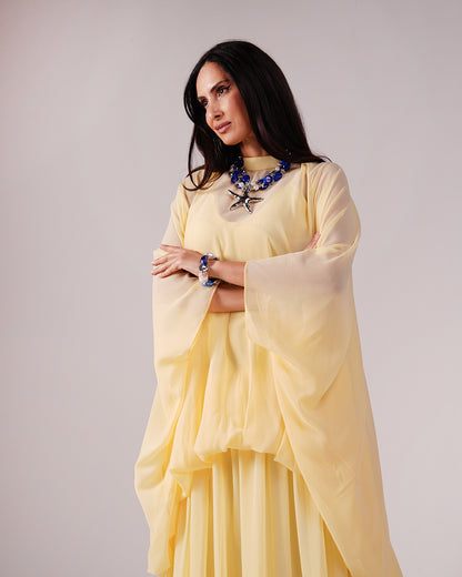 Front view showing the Élan yellow dress’s layered top and loose sleeves.