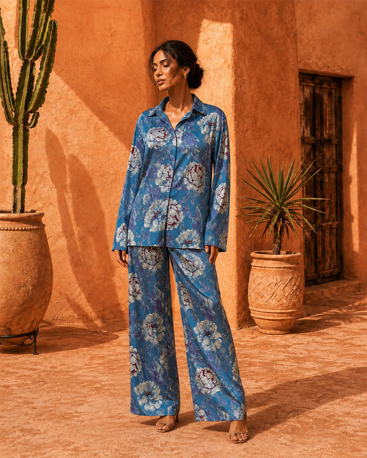 Model wearing the Sahara Bloom blue floral silk co-ord set with a collared shirt and wide-leg trousers.