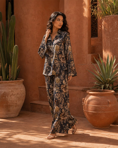 Model wearing the Sahara Bloom midnight navy floral silk two-piece set in a terracotta courtyard.