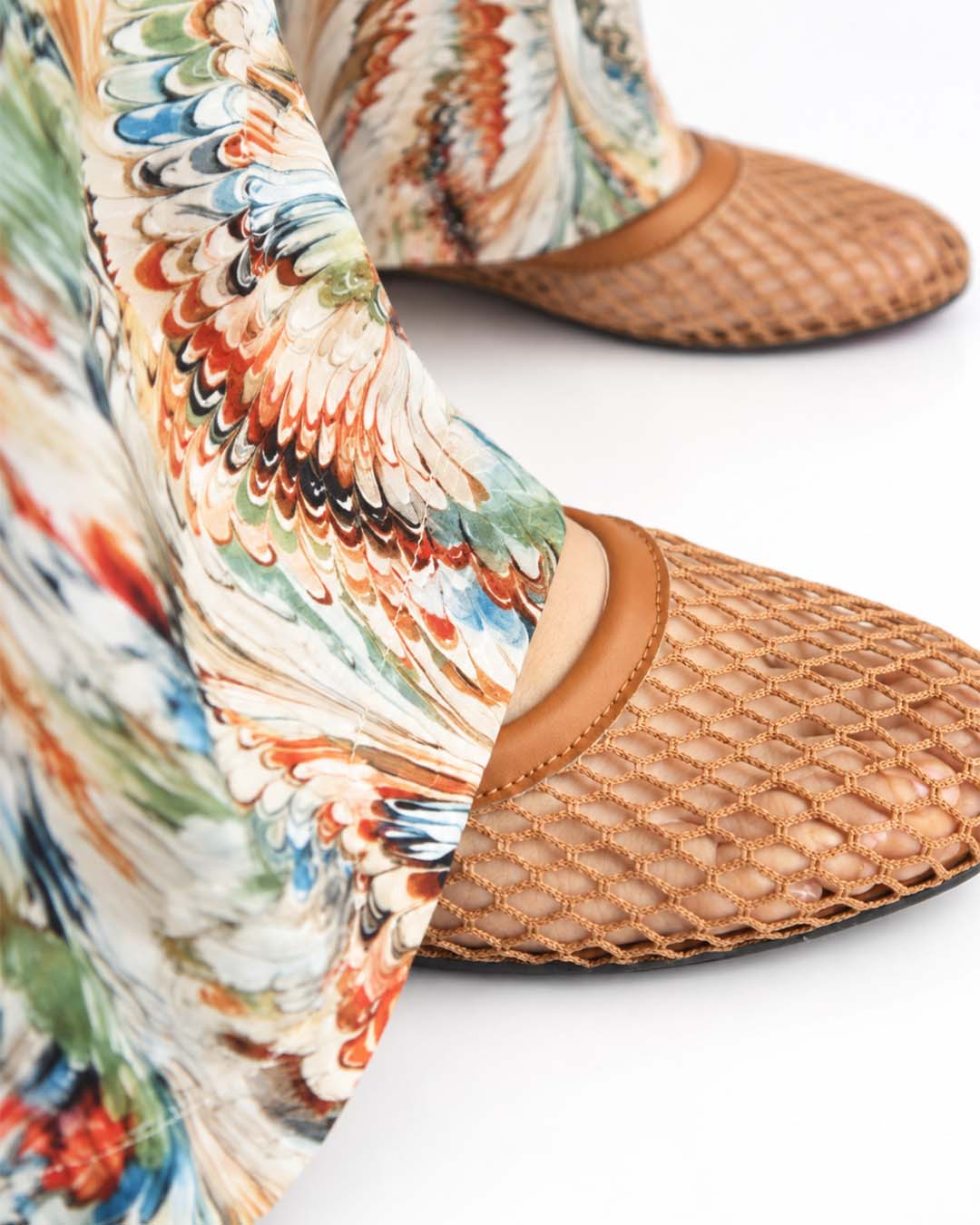 Close-up of L’Artiste printed wide-leg trouser hems draping over tan woven flats.